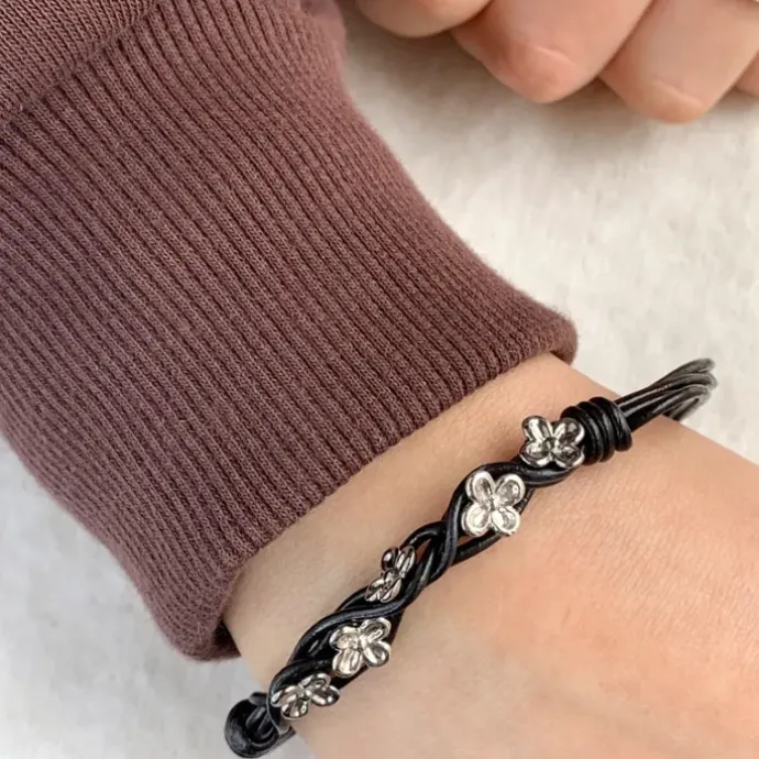 Sort armbånd i læder med blomstervedhæng i rhodineret sølv